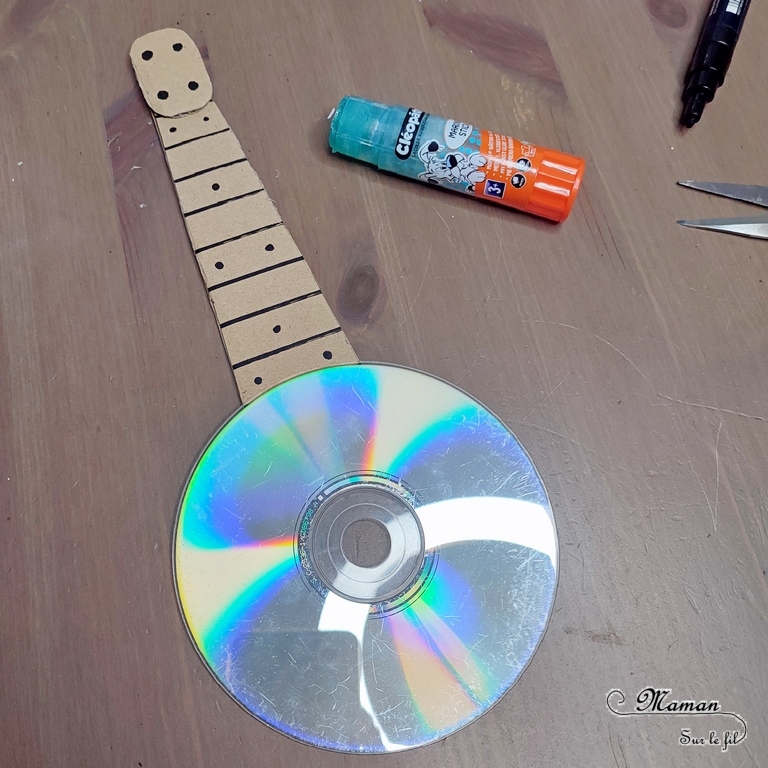 Activité créative et manuelle enfants - Fabriquer des banjos avec des CD et du carton - Bricolage récup' avec des pompons - Récup, recyclage, surcyclage - Découpage, bricolage, collage - Bricolage facile et rapide pour un thème sur la fête de la musique - Arts visuels et atelier Maternelle et élémentaire - Créativité - Cycle 1 ou 2 - tutoriel photos - mslf