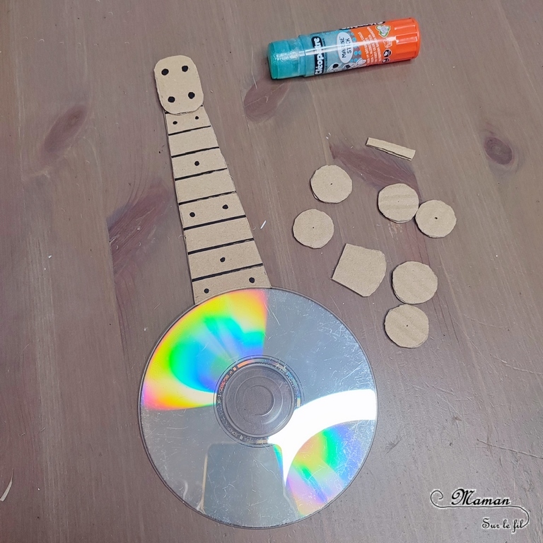 Activité créative et manuelle enfants - Fabriquer des banjos avec des CD et du carton - Bricolage récup' avec des pompons - Récup, recyclage, surcyclage - Découpage, bricolage, collage - Bricolage facile et rapide pour un thème sur la fête de la musique - Arts visuels et atelier Maternelle et élémentaire - Créativité - Cycle 1 ou 2 - tutoriel photos - mslf