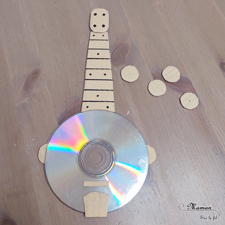 Activité créative et manuelle enfants - Fabriquer des banjos avec des CD et du carton - Bricolage récup' avec des pompons - Récup, recyclage, surcyclage - Découpage, bricolage, collage - Bricolage facile et rapide pour un thème sur la fête de la musique - Arts visuels et atelier Maternelle et élémentaire - Créativité - Cycle 1 ou 2 - tutoriel photos - mslf