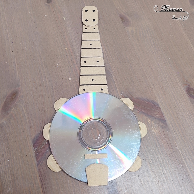 Activité créative et manuelle enfants - Fabriquer des banjos avec des CD et du carton - Bricolage récup' avec des pompons - Récup, recyclage, surcyclage - Découpage, bricolage, collage - Bricolage facile et rapide pour un thème sur la fête de la musique - Arts visuels et atelier Maternelle et élémentaire - Créativité - Cycle 1 ou 2 - tutoriel photos - mslf