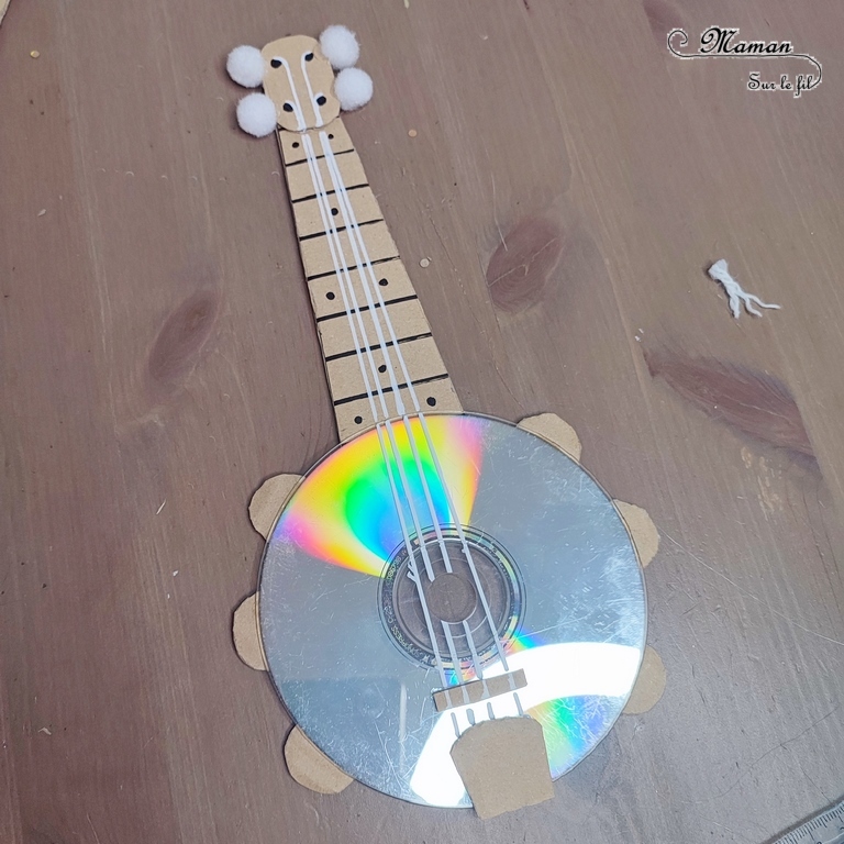 Activité créative et manuelle enfants - Fabriquer des banjos avec des CD et du carton - Bricolage récup' avec des pompons - Récup, recyclage, surcyclage - Découpage, bricolage, collage - Bricolage facile et rapide pour un thème sur la fête de la musique - Arts visuels et atelier Maternelle et élémentaire - Créativité - Cycle 1 ou 2 - tutoriel photos - mslf