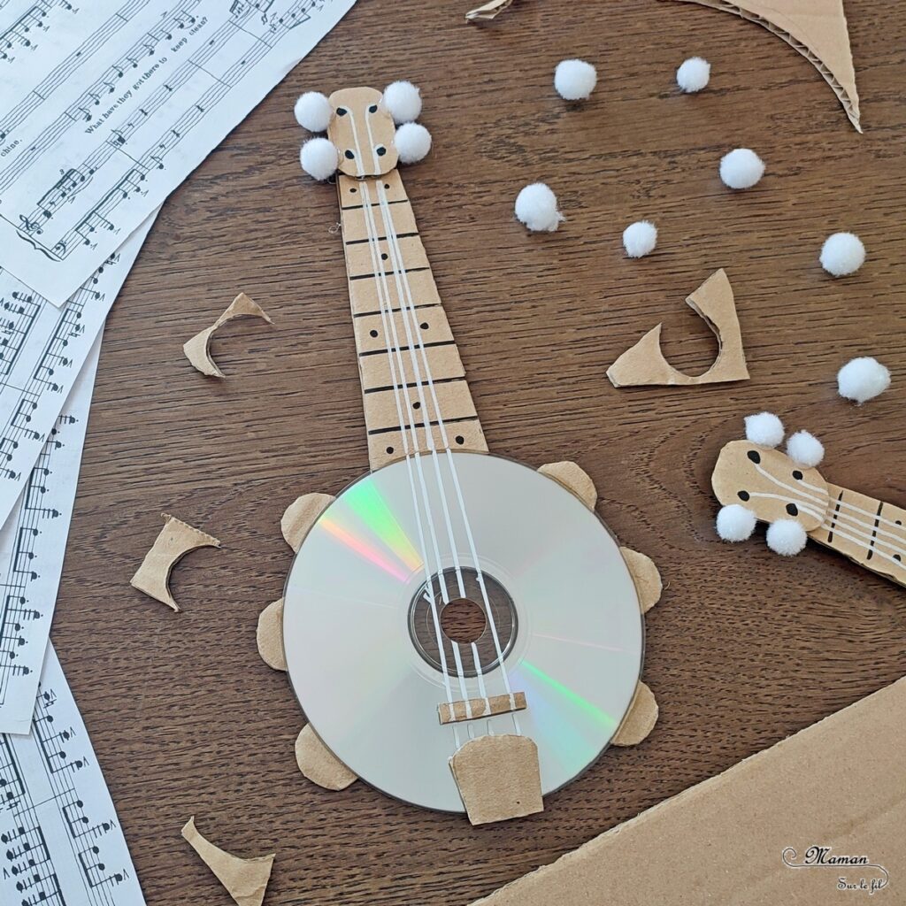 Activité créative et manuelle enfants - Fabriquer des banjos avec des CD et du carton - Bricolage récup' avec des pompons - Récup, recyclage, surcyclage - Découpage, bricolage, collage - Bricolage facile et rapide pour un thème sur la fête de la musique - Arts visuels et atelier Maternelle et élémentaire - Créativité - Cycle 1 ou 2 - tutoriel photos - mslf