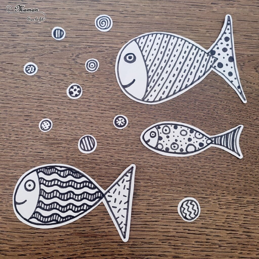 Créer des poissons graphiques sur fond bleu : activité créative et manuelle enfants - Découpage en vagues et collage de papiers bleus pour le fond - Dessin et graphismes en noir pour les poissons - Contraste entre les couleurs vives du fond et le noir et blanc des poissons - Arts visuels et Bricolage - Thème Poissons d'avril, animaux marins, 1er avril, été - Bricolage facile et rapide - Arts visuels et atelier Maternelle et élémentaire - Créativité - Cycle 1 ou 2 - tutoriel photos - mslf