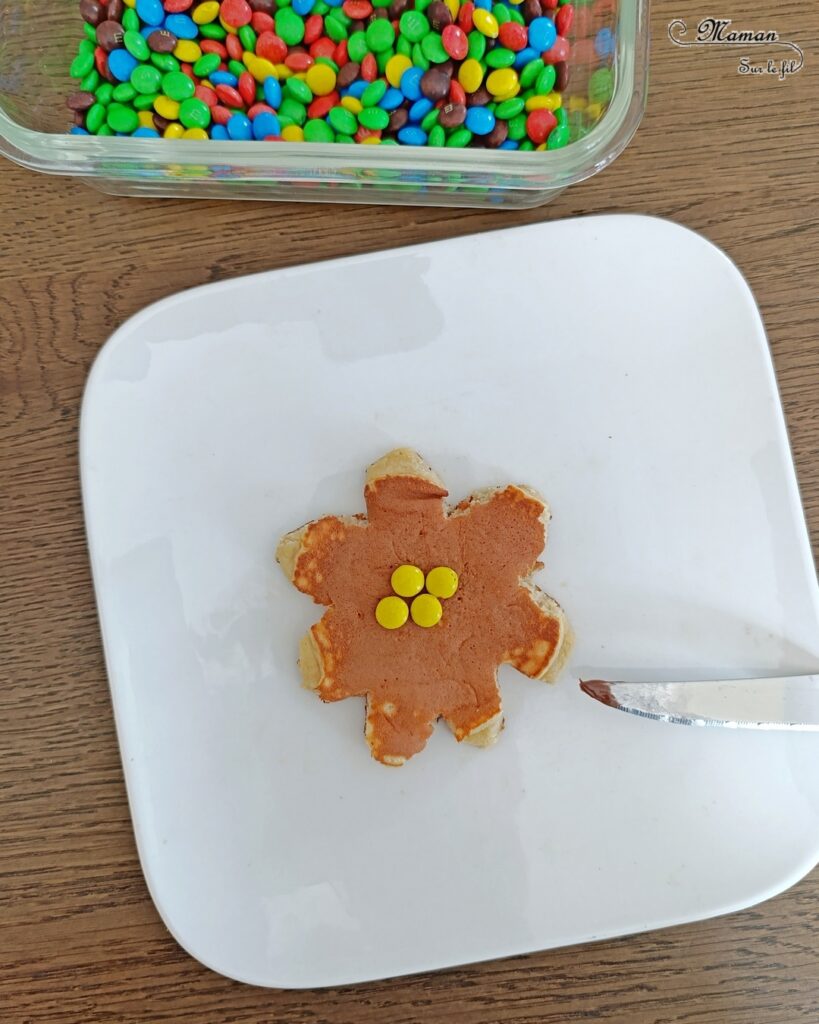 Transformer un pancake en fleur avec des bonbons : activité créative, cuisine et manuelle enfants - Cuisiner avec les enfants - Recette de pancake sans sucre ajouté avec de la compote de pommes - Décoration avec des bonbons type smarties ou mini M&M's - Goûter ou petit déjeuner rigolo - Simple, coloré et joli - Thème Fleurs, printemps, couleurs - Décoration sympa et facile - Cuisine maternelle et élémentaire - Cycles 1 et 2 - Créativité - tutoriel photos - mslf