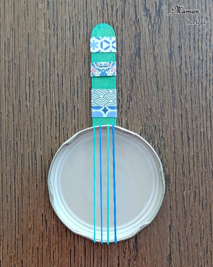 Fabriquer des mini banjos colorés en récup' : activité créative, récup et manuelle enfants - Recyclage, surcyclage de bouchons métalliques, d'élastiques et de bâtonnets en bois colorés - Bricolage rapide pour la fête de la musique - Découpage et collage de papier à motifs - Instruments de musique DIY, fait maison - Thème Fête de la musique - Bricolage et décoration sympa et facile - Arts visuels maternelle et élémentaire - Cycles 1 et 2 - Créativité - tutoriel photos - mslf