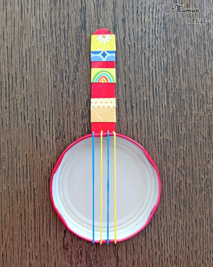 Fabriquer des mini banjos colorés en récup' : activité créative, récup et manuelle enfants - Recyclage, surcyclage de bouchons métalliques, d'élastiques et de bâtonnets en bois colorés - Bricolage rapide pour la fête de la musique - Découpage et collage de papier à motifs - Instruments de musique DIY, fait maison - Thème Fête de la musique - Bricolage et décoration sympa et facile - Arts visuels maternelle et élémentaire - Cycles 1 et 2 - Créativité - tutoriel photos - mslf