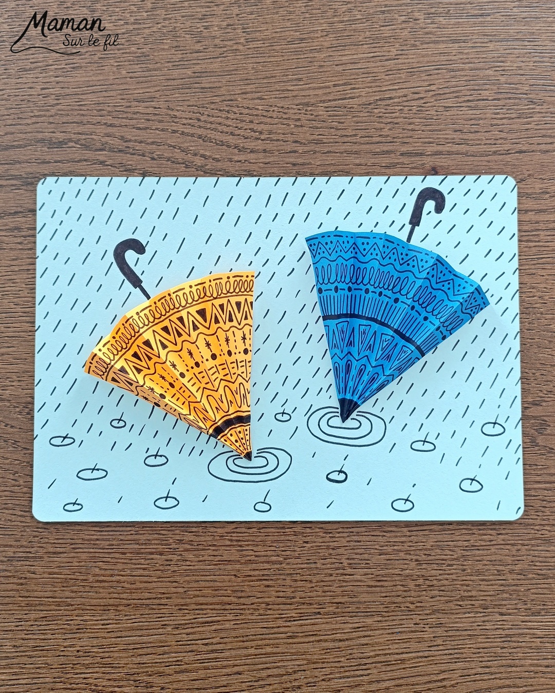 Créer des parapluies graphiques en volume : activité créative, papier et manuelle enfants - Dessin de cercles au compas - Graphismes et dessins noirs pour les décors du parapluie - Découpage et pliage pour l'accordéon - Collage et dessins pour donner l'impression que les parapluies sont posés sous la pluie - Traits obliques - Bricolage et décoration DIY et facile - Bricolage Fait maison, décoration - Thème Météo, Pluie, Nuage, Ciel, Automne - Bricolage sympa et facile - Arts visuels Maternelle et cycle 2 - Maternelle et élémentaire - Créativité - Cycle 1 ou 2 - tutoriel photos - mslf