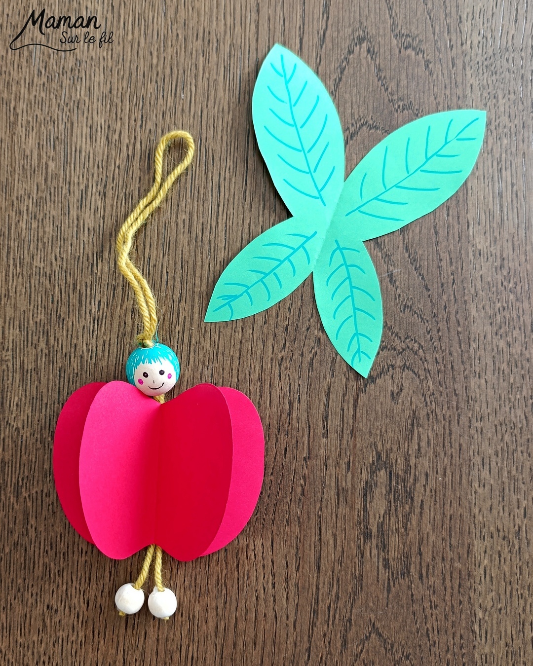 Fabriquer une fée pomme à suspendre : activité créative, papier et manuelle enfants - Pomme en volume en découpant et collant plusieurs pommes - Découpage, collage - Tête et pieds avec des perles en bois - Suspension avec un morceau de laine - Ailes de la fée comme des feuilles - Bricolage et décoration DIY et facile - Bricolage Fait maison, décoration - Thème pommes, fruits et légumes, potager, verger, automne, printemps, créatures légendaires, imaginaires, fées - Bricolage sympa et facile - Arts visuels Maternelle et cycle 2 - Maternelle et élémentaire - Créativité - Cycle 1 ou 2 - tutoriel photos - mslf