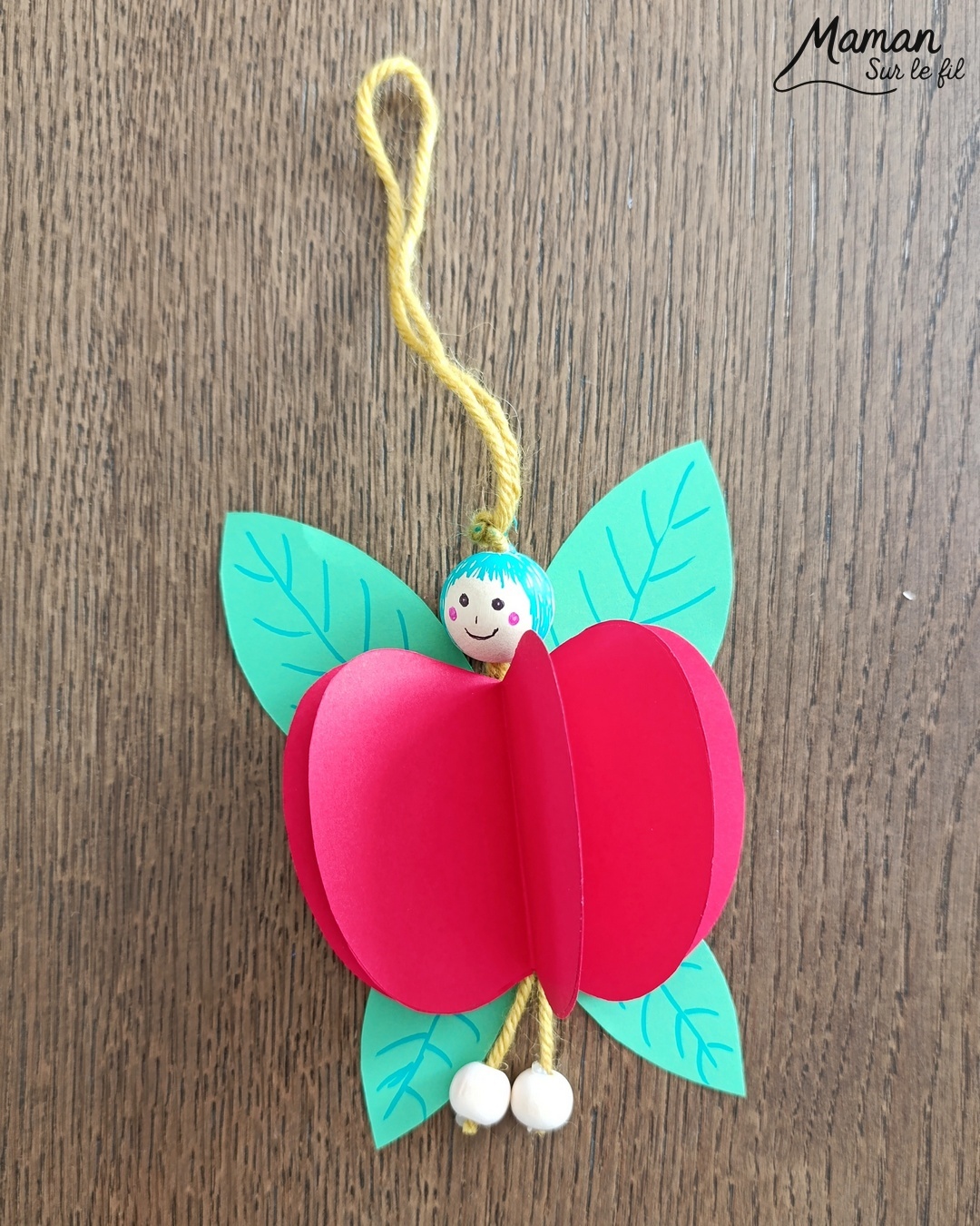 Fabriquer une fée pomme à suspendre : activité créative, papier et manuelle enfants - Pomme en volume en découpant et collant plusieurs pommes - Découpage, collage - Tête et pieds avec des perles en bois - Suspension avec un morceau de laine - Ailes de la fée comme des feuilles - Bricolage et décoration DIY et facile - Bricolage Fait maison, décoration - Thème pommes, fruits et légumes, potager, verger, automne, printemps, créatures légendaires, imaginaires, fées - Bricolage sympa et facile - Arts visuels Maternelle et cycle 2 - Maternelle et élémentaire - Créativité - Cycle 1 ou 2 - tutoriel photos - mslf