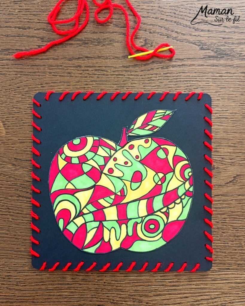 Dessiner et colorier une pomme graphique et son cadre en laine : activité créative, dessin, motricité fine et manuelle enfants - Dessin de la pomme et des graphismes intérieurs au feutre noir - Coloriage aux couleurs des pommes : jaune, vert et rouge - Découpage et collage sur fond noir pour contraste - Cadre tissé en laine rouge - Bricolage et décoration DIY et facile - Bricolage Fait maison, décoration - Création façon art thérapie ou zen art - Thème pommes, fruits et légumes, potager, verger, automne - Bricolage sympa et facile - Arts visuels Maternelle et cycle 2 - Maternelle et élémentaire - Créativité - Cycle 1 ou 2 - tutoriel photos - mslf