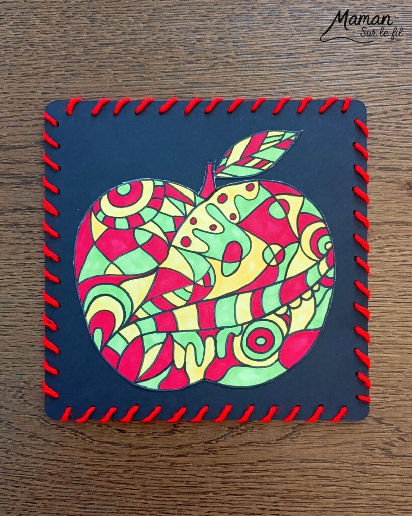 Dessiner et colorier une pomme graphique et son cadre en laine : activité créative, dessin, motricité fine et manuelle enfants - Dessin de la pomme et des graphismes intérieurs au feutre noir - Coloriage aux couleurs des pommes : jaune, vert et rouge - Découpage et collage sur fond noir pour contraste - Cadre tissé en laine rouge - Bricolage et décoration DIY et facile - Bricolage Fait maison, décoration - Création façon art thérapie ou zen art - Thème pommes, fruits et légumes, potager, verger, automne - Bricolage sympa et facile - Arts visuels Maternelle et cycle 2 - Maternelle et élémentaire - Créativité - Cycle 1 ou 2 - tutoriel photos - mslf