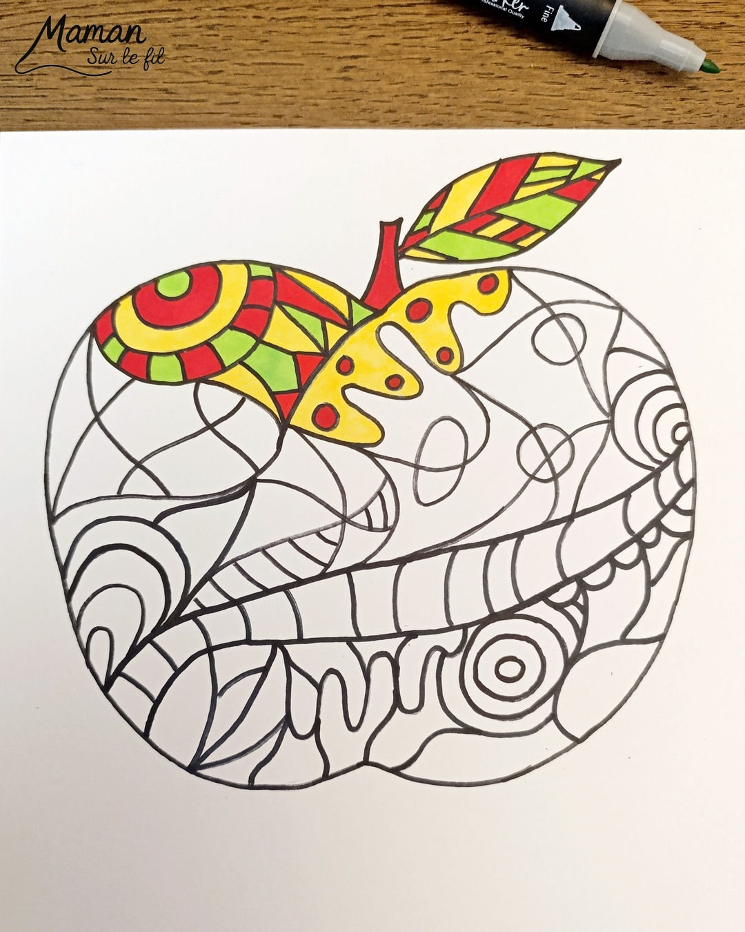 Dessiner et colorier une pomme graphique et son cadre en laine : activité créative, dessin, motricité fine et manuelle enfants - Dessin de la pomme et des graphismes intérieurs au feutre noir - Coloriage aux couleurs des pommes : jaune, vert et rouge - Découpage et collage sur fond noir pour contraste - Cadre tissé en laine rouge - Bricolage et décoration DIY et facile - Bricolage Fait maison, décoration - Création façon art thérapie ou zen art - Thème pommes, fruits et légumes, potager, verger, automne - Bricolage sympa et facile - Arts visuels Maternelle et cycle 2 - Maternelle et élémentaire - Créativité - Cycle 1 ou 2 - tutoriel photos - mslf