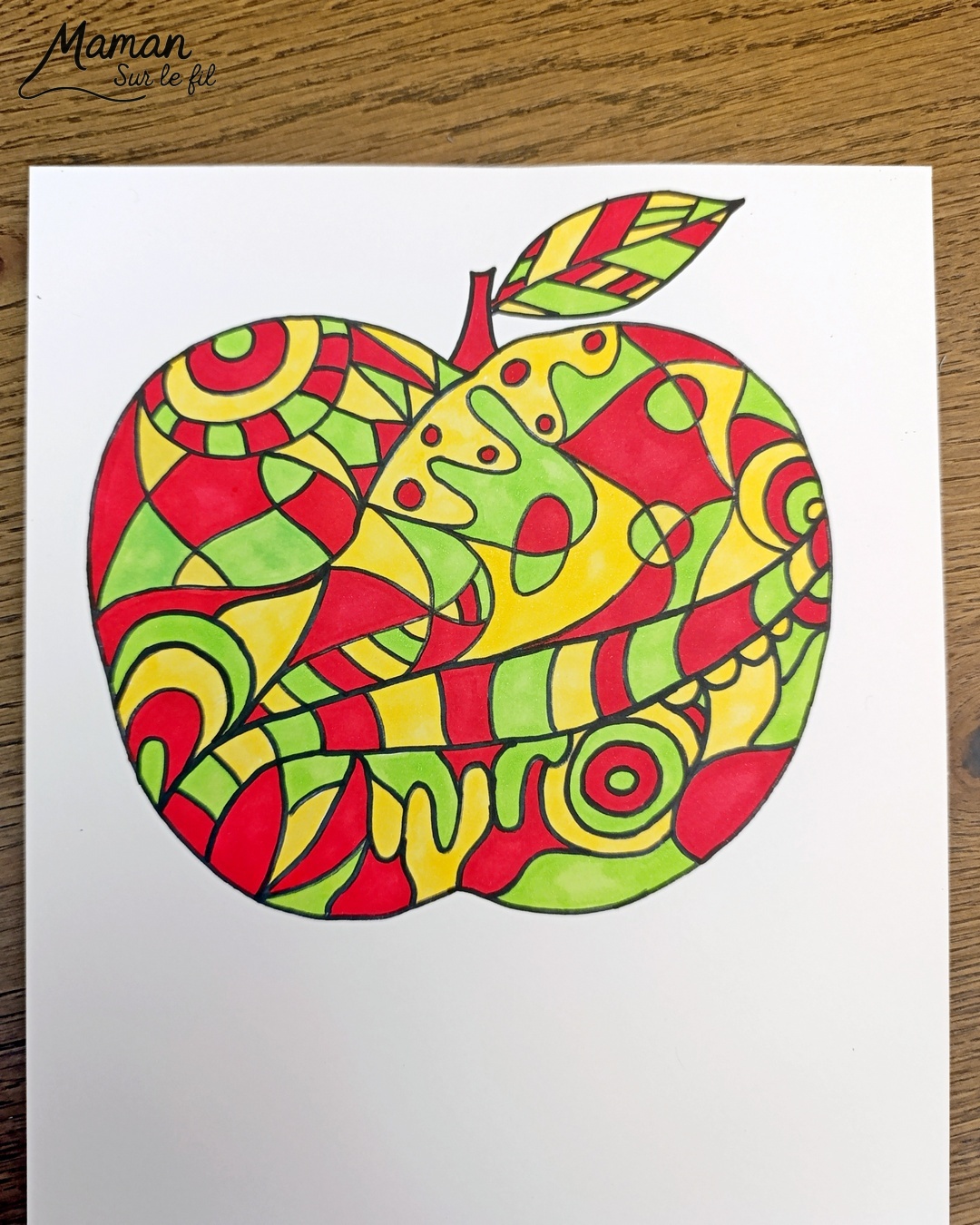 Dessiner et colorier une pomme graphique et son cadre en laine : activité créative, dessin, motricité fine et manuelle enfants - Dessin de la pomme et des graphismes intérieurs au feutre noir - Coloriage aux couleurs des pommes : jaune, vert et rouge - Découpage et collage sur fond noir pour contraste - Cadre tissé en laine rouge - Bricolage et décoration DIY et facile - Bricolage Fait maison, décoration - Création façon art thérapie ou zen art - Thème pommes, fruits et légumes, potager, verger, automne - Bricolage sympa et facile - Arts visuels Maternelle et cycle 2 - Maternelle et élémentaire - Créativité - Cycle 1 ou 2 - tutoriel photos - mslf