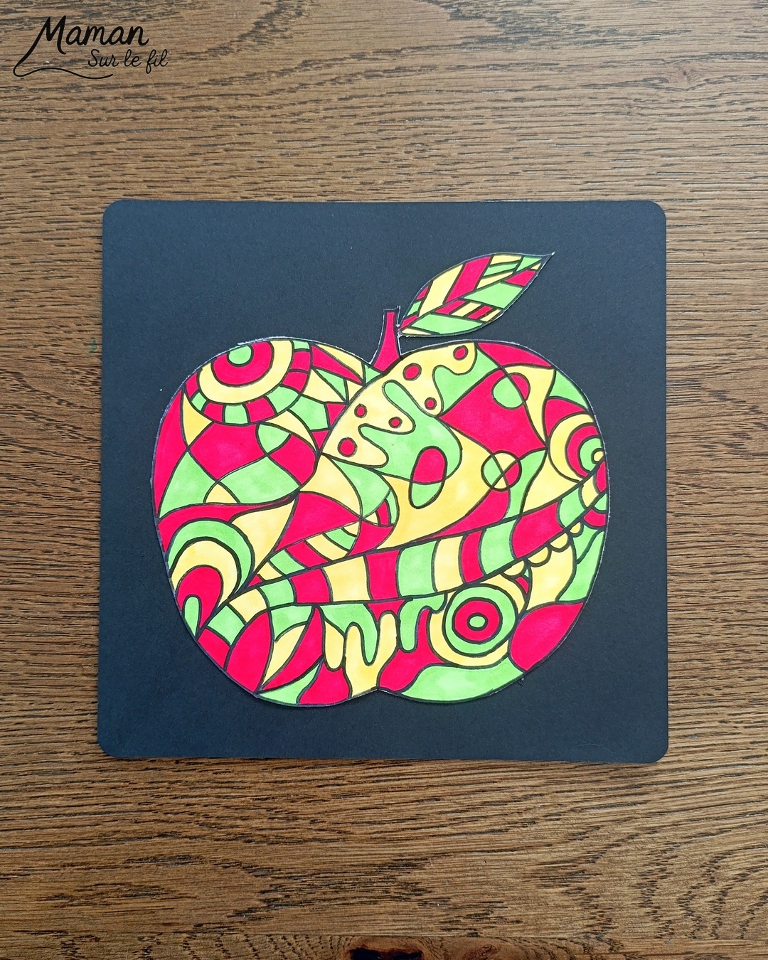 Dessiner et colorier une pomme graphique et son cadre en laine : activité créative, dessin, motricité fine et manuelle enfants - Dessin de la pomme et des graphismes intérieurs au feutre noir - Coloriage aux couleurs des pommes : jaune, vert et rouge - Découpage et collage sur fond noir pour contraste - Cadre tissé en laine rouge - Bricolage et décoration DIY et facile - Bricolage Fait maison, décoration - Création façon art thérapie ou zen art - Thème pommes, fruits et légumes, potager, verger, automne - Bricolage sympa et facile - Arts visuels Maternelle et cycle 2 - Maternelle et élémentaire - Créativité - Cycle 1 ou 2 - tutoriel photos - mslf