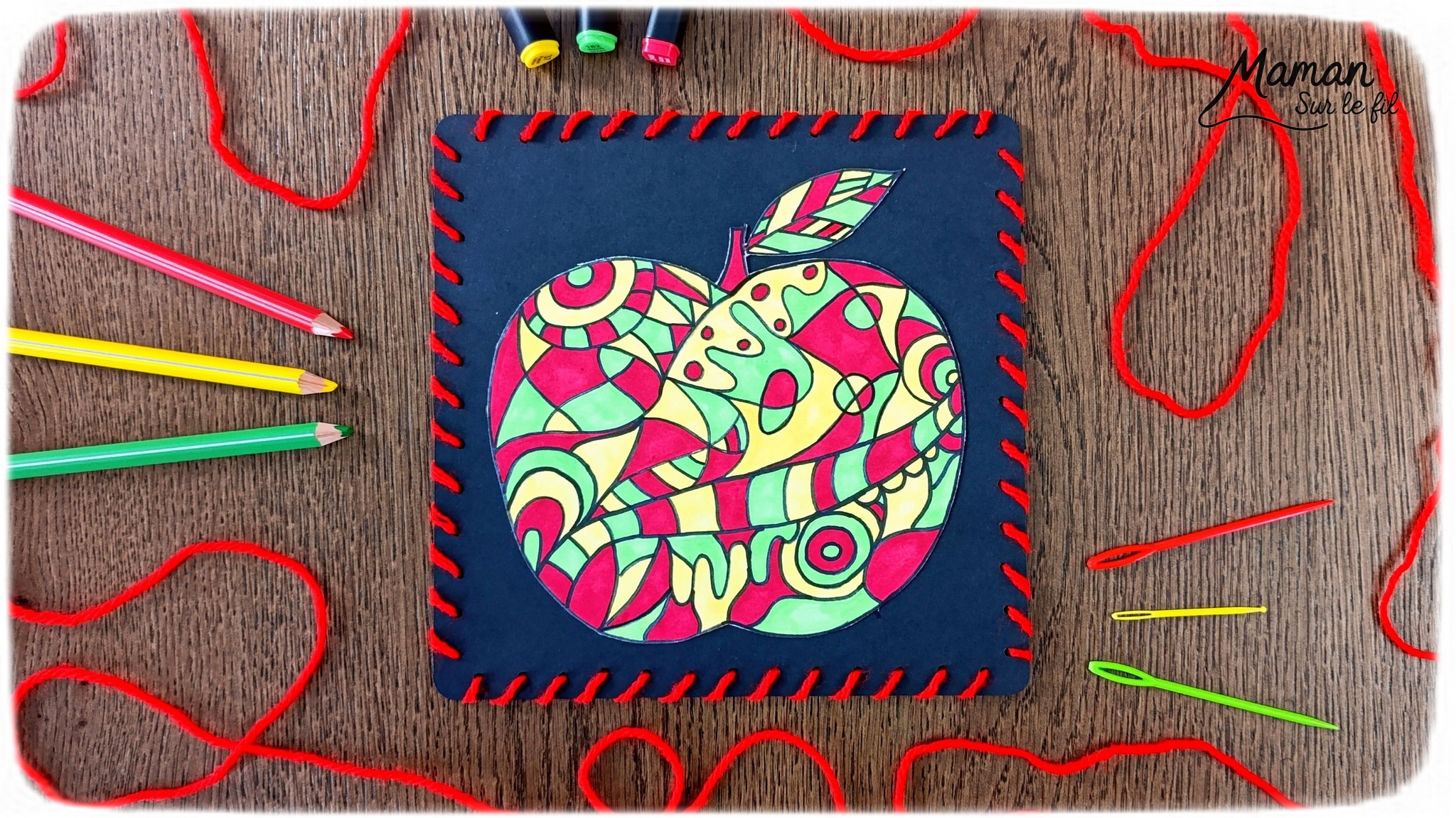 Dessiner et colorier une pomme graphique et son cadre en laine : activité créative, dessin, motricité fine et manuelle enfants - Dessin de la pomme et des graphismes intérieurs au feutre noir - Coloriage aux couleurs des pommes : jaune, vert et rouge - Découpage et collage sur fond noir pour contraste - Cadre tissé en laine rouge - Bricolage et décoration DIY et facile - Bricolage Fait maison, décoration - Création façon art thérapie ou zen art - Thème pommes, fruits et légumes, potager, verger, automne - Bricolage sympa et facile - Arts visuels Maternelle et cycle 2 - Maternelle et élémentaire - Créativité - Cycle 1 ou 2 - tutoriel photos - mslf