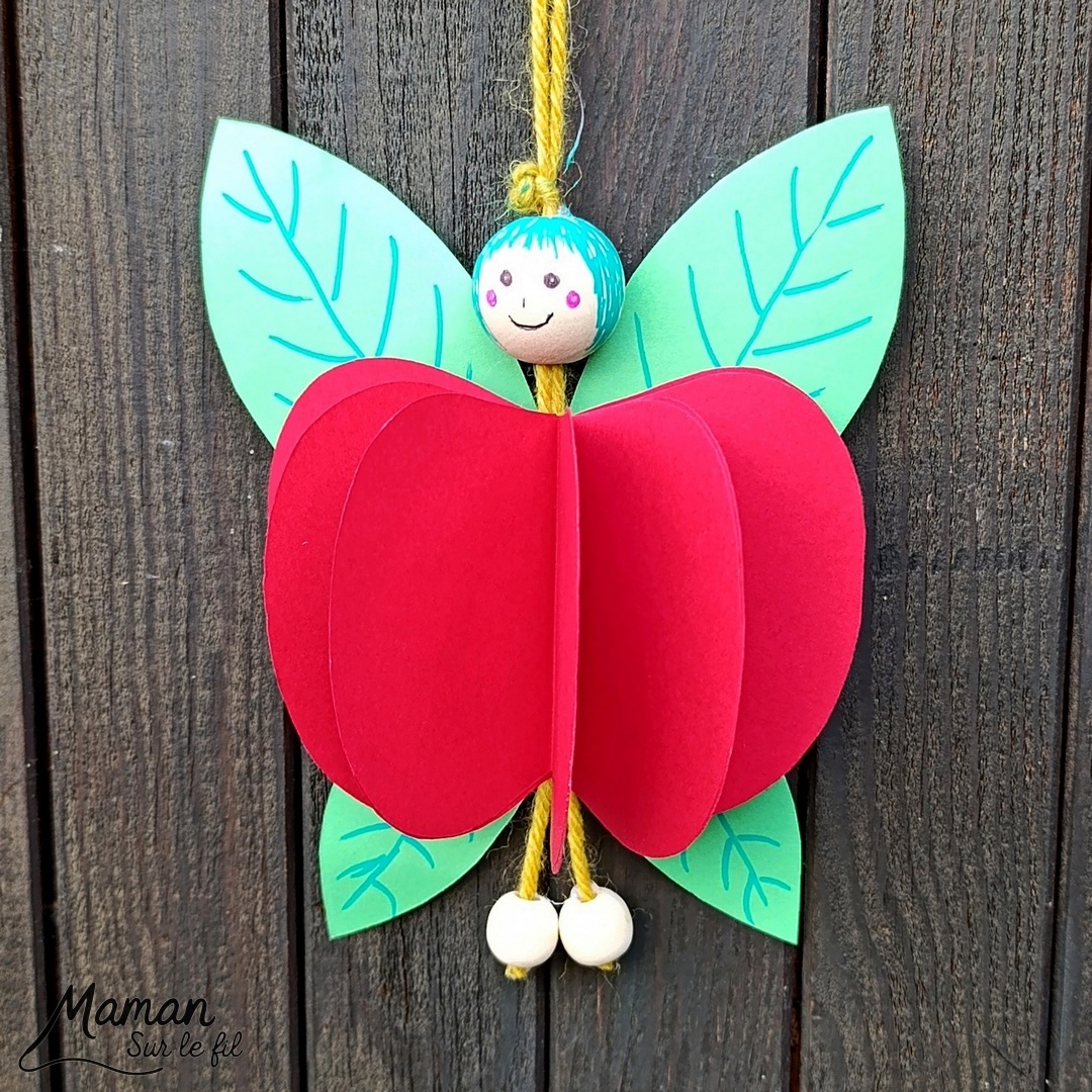 Fabriquer une fée pomme à suspendre : activité créative, papier et manuelle enfants - Pomme en volume en découpant et collant plusieurs pommes - Découpage, collage - Tête et pieds avec des perles en bois - Suspension avec un morceau de laine - Ailes de la fée comme des feuilles - Bricolage et décoration DIY et facile - Bricolage Fait maison, décoration - Thème pommes, fruits et légumes, potager, verger, automne, printemps, créatures légendaires, imaginaires, fées - Bricolage sympa et facile - Arts visuels Maternelle et cycle 2 - Maternelle et élémentaire - Créativité - Cycle 1 ou 2 - tutoriel photos - mslf