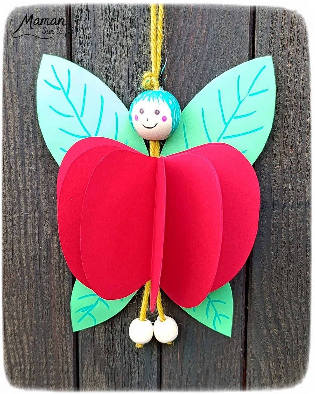 Fabriquer une fée pomme à suspendre : activité créative, papier et manuelle enfants - Pomme en volume en découpant et collant plusieurs pommes - Découpage, collage - Tête et pieds avec des perles en bois - Suspension avec un morceau de laine - Ailes de la fée comme des feuilles - Bricolage et décoration DIY et facile - Bricolage Fait maison, décoration - Thème pommes, fruits et légumes, potager, verger, automne, printemps, créatures légendaires, imaginaires, fées - Bricolage sympa et facile - Arts visuels Maternelle et cycle 2 - Maternelle et élémentaire - Créativité - Cycle 1 ou 2 - tutoriel photos - mslf