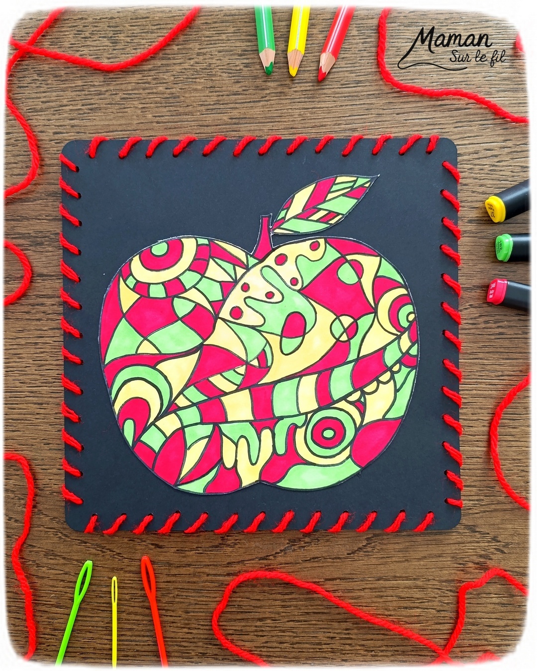 Dessiner et colorier une pomme graphique et son cadre en laine : activité créative, dessin, motricité fine et manuelle enfants - Dessin de la pomme et des graphismes intérieurs au feutre noir - Coloriage aux couleurs des pommes : jaune, vert et rouge - Découpage et collage sur fond noir pour contraste - Cadre tissé en laine rouge - Bricolage et décoration DIY et facile - Bricolage Fait maison, décoration - Création façon art thérapie ou zen art - Thème pommes, fruits et légumes, potager, verger, automne - Bricolage sympa et facile - Arts visuels Maternelle et cycle 2 - Maternelle et élémentaire - Créativité - Cycle 1 ou 2 - tutoriel photos - mslf