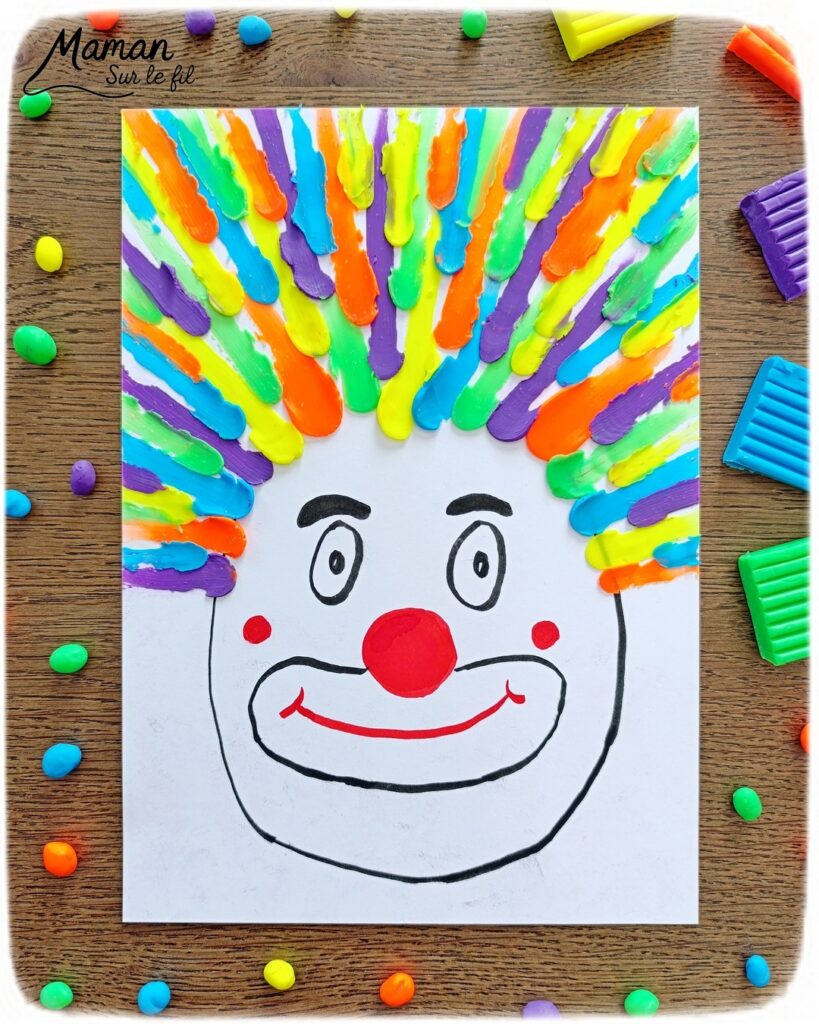 Créer un clown aux cheveux fous en pâte à modeler fluo étalée au doigt : activité créative, sensoriel et manuelle enfants - Dessin d'une tête de clown aux feutres noir et rouge - Cheveux multicolore créés en étalant des boules de pâte à modeler - Motricité fine, musculation des doigts, sensoriel - Bricolage facile, coloré et rigolo - Thème Carnaval, Mardi-Gras, cirque, anniversaire et fêtes - Bricolage et décoration sympa et facile - Arts visuels maternelle et élémentaire - Cycles 1 et 2 - Créativité - tutoriel photos et vidéo - mslf