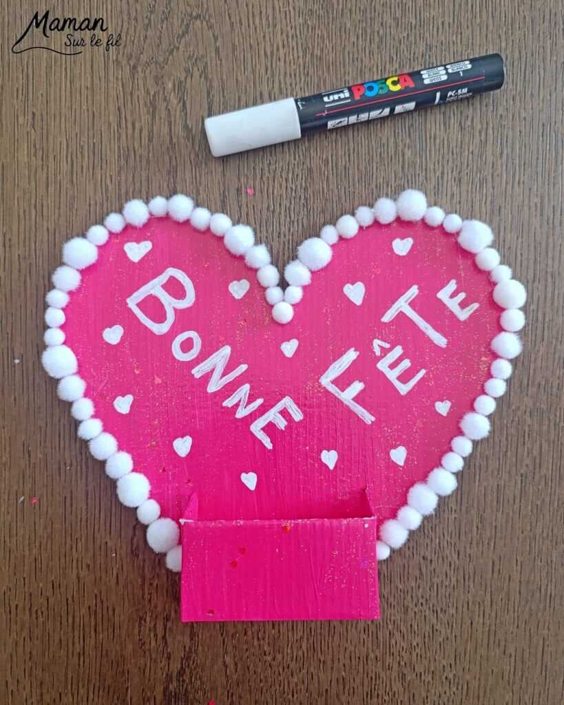 Fabriquer une carte et un support de téléphone en carton pour la fête des mères : activité créative, peinture, dessins et manuelle enfants - Matériel et supports en carton de chez Cléopâtre - Idée Cadeau à petit prix - Peinture rose, empreintes de doigts pour les coeurs, paillettes avec gel pailleté plein d'amour - Décor avec pompons blanc et message blanc et noir - Cadeau à offrir DIY Fait maison - Décoration DIY Fait maison - Arts visuels et Bricolage facile - Thème amour, amitié, Saint Valentin, fête des mères, grands-mères, pères, grands-pères - Bricolage et décoration sympa et facile - Arts visuels maternelle et élémentaire - Cycles 1 et 2 - Créativité - tutoriel photos - mslf