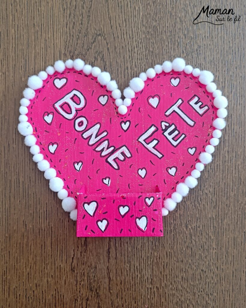Fabriquer une carte et un support de téléphone en carton pour la fête des mères : activité créative, peinture, dessins et manuelle enfants - Matériel et supports en carton de chez Cléopâtre - Idée Cadeau à petit prix - Peinture rose, empreintes de doigts pour les coeurs, paillettes avec gel pailleté plein d'amour - Décor avec pompons blanc et message blanc et noir - Cadeau à offrir DIY Fait maison - Décoration DIY Fait maison - Arts visuels et Bricolage facile - Thème amour, amitié, Saint Valentin, fête des mères, grands-mères, pères, grands-pères - Bricolage et décoration sympa et facile - Arts visuels maternelle et élémentaire - Cycles 1 et 2 - Créativité - tutoriel photos - mslf