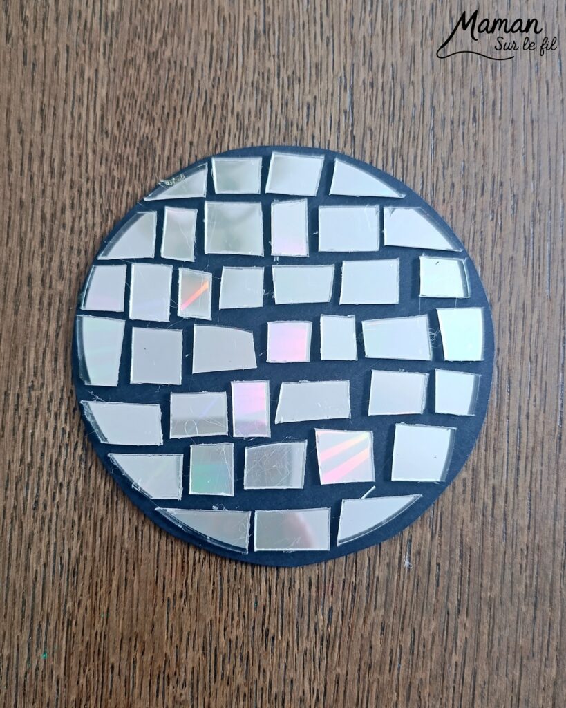 Fabriquer des boules à facettes avec des vieux CD : activité créative, récup' et manuelle enfants - Recyclage, surcyclage d'anciens compact disc (CD) abîmés - Découpage en morceaux pour le côté mosaïque - Base avec un autre CD et du papier aluminium ou noir - Collage - Bolduc argenté pour en faire une suspension - Décoration DIY Fait maison - Arts visuels et Bricolage facile - Thème fête de la musique, instruments de musique, anniversaire, jour de l'an, nouvelle année, été - Bricolage et décoration sympa et facile - Arts visuels maternelle et élémentaire - Cycles 1 et 2 - Créativité - tutoriel photos - mslf