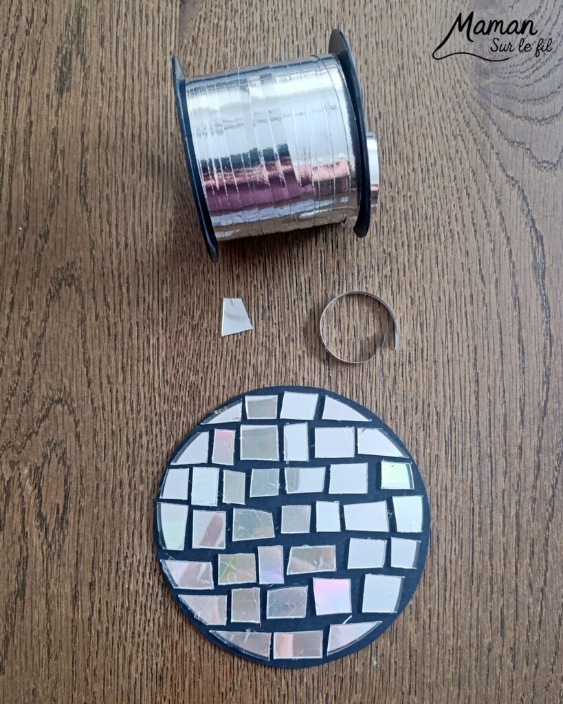 Fabriquer des boules à facettes avec des vieux CD : activité créative, récup' et manuelle enfants - Recyclage, surcyclage d'anciens compact disc (CD) abîmés - Découpage en morceaux pour le côté mosaïque - Base avec un autre CD et du papier aluminium ou noir - Collage - Bolduc argenté pour en faire une suspension - Décoration DIY Fait maison - Arts visuels et Bricolage facile - Thème fête de la musique, instruments de musique, anniversaire, jour de l'an, nouvelle année, été - Bricolage et décoration sympa et facile - Arts visuels maternelle et élémentaire - Cycles 1 et 2 - Créativité - tutoriel photos - mslf
