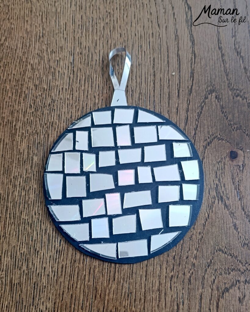 Fabriquer des boules à facettes avec des vieux CD : activité créative, récup' et manuelle enfants - Recyclage, surcyclage d'anciens compact disc (CD) abîmés - Découpage en morceaux pour le côté mosaïque - Base avec un autre CD et du papier aluminium ou noir - Collage - Bolduc argenté pour en faire une suspension - Décoration DIY Fait maison - Arts visuels et Bricolage facile - Thème fête de la musique, instruments de musique, anniversaire, jour de l'an, nouvelle année, été - Bricolage et décoration sympa et facile - Arts visuels maternelle et élémentaire - Cycles 1 et 2 - Créativité - tutoriel photos - mslf