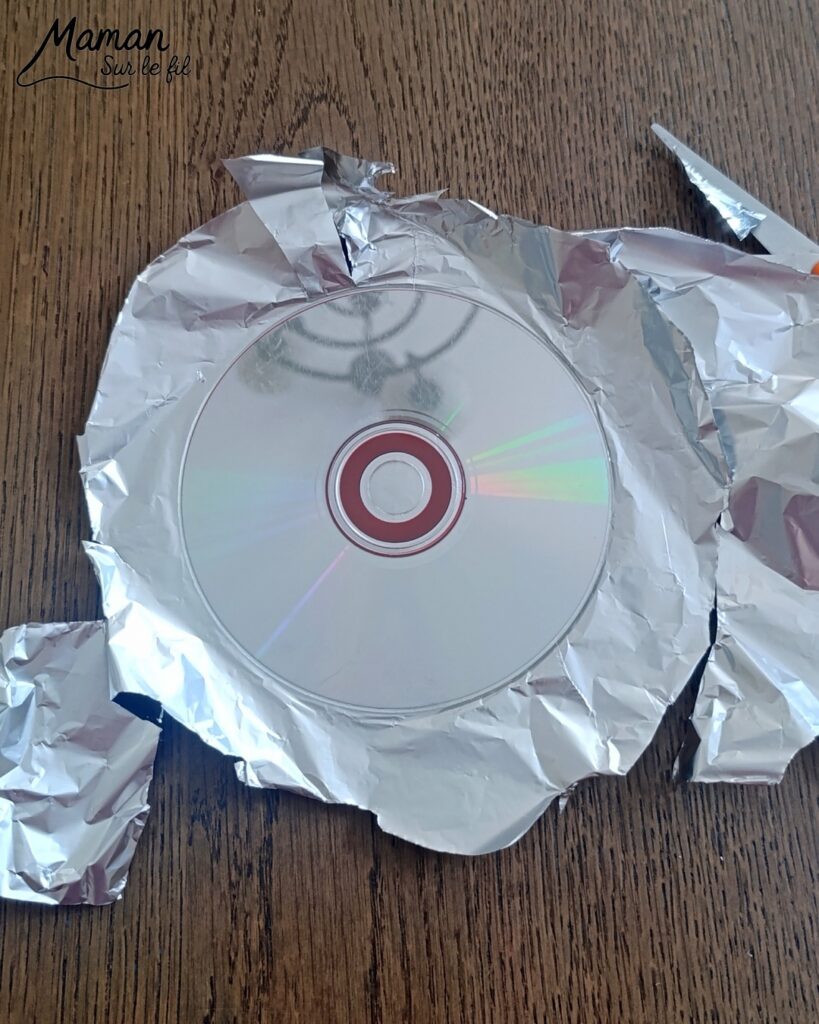 Fabriquer des boules à facettes avec des vieux CD : activité créative, récup' et manuelle enfants - Recyclage, surcyclage d'anciens compact disc (CD) abîmés - Découpage en morceaux pour le côté mosaïque - Base avec un autre CD et du papier aluminium ou noir - Collage - Bolduc argenté pour en faire une suspension - Décoration DIY Fait maison - Arts visuels et Bricolage facile - Thème fête de la musique, instruments de musique, anniversaire, jour de l'an, nouvelle année, été - Bricolage et décoration sympa et facile - Arts visuels maternelle et élémentaire - Cycles 1 et 2 - Créativité - tutoriel photos - mslf