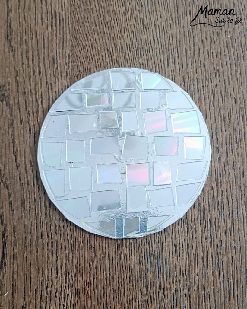 Fabriquer des boules à facettes avec des vieux CD : activité créative, récup' et manuelle enfants - Recyclage, surcyclage d'anciens compact disc (CD) abîmés - Découpage en morceaux pour le côté mosaïque - Base avec un autre CD et du papier aluminium ou noir - Collage - Bolduc argenté pour en faire une suspension - Décoration DIY Fait maison - Arts visuels et Bricolage facile - Thème fête de la musique, instruments de musique, anniversaire, jour de l'an, nouvelle année, été - Bricolage et décoration sympa et facile - Arts visuels maternelle et élémentaire - Cycles 1 et 2 - Créativité - tutoriel photos - mslf