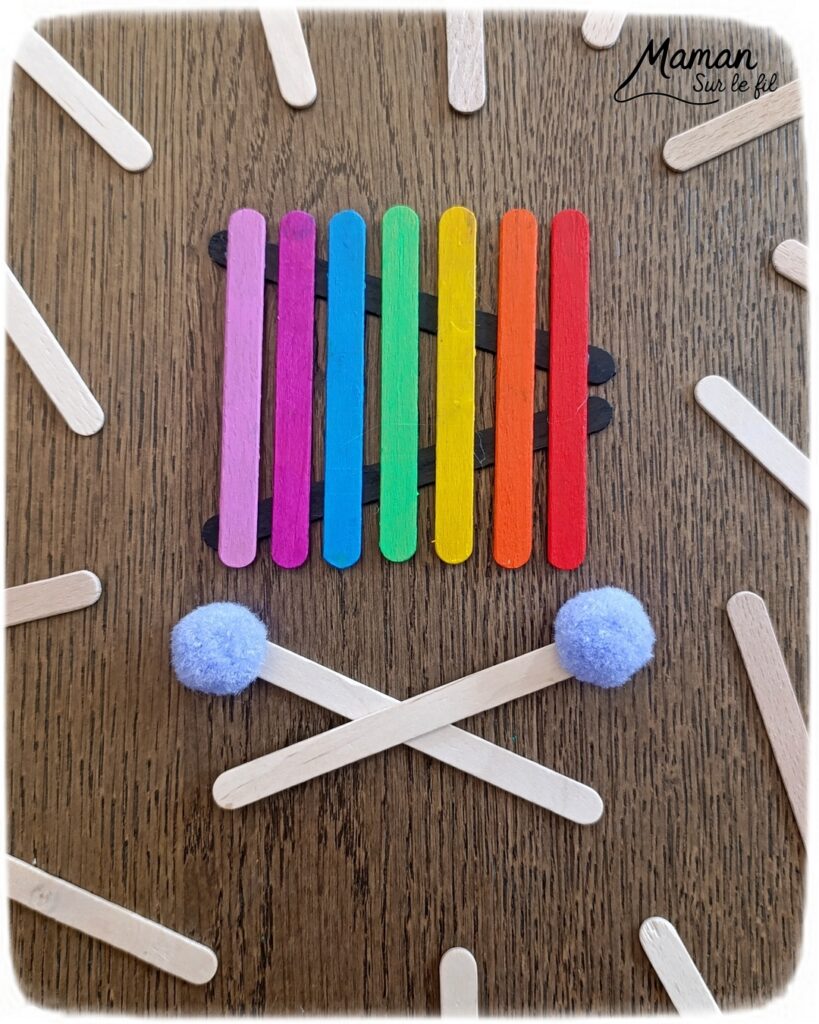 Fabriquer des instruments de musique avec des bâtonnets de glace en bois : activité créative, récup', peinture et manuelle enfants - Recyclage, surcyclage de bâtonnets de glace en bois - Gouache en stick aux couleurs de l'arc-en-ciel pour le xylophone - Pompons pour les baguettes - Noir et blanc pour le clavier de piano - Décoration DIY Fait maison - Arts visuels et Bricolage facile - Thème fête de la musique, instruments de musique, été - Bricolage et décoration sympa et facile - Arts visuels maternelle et élémentaire - Cycles 1 et 2 - Créativité - tutoriel photos - mslf