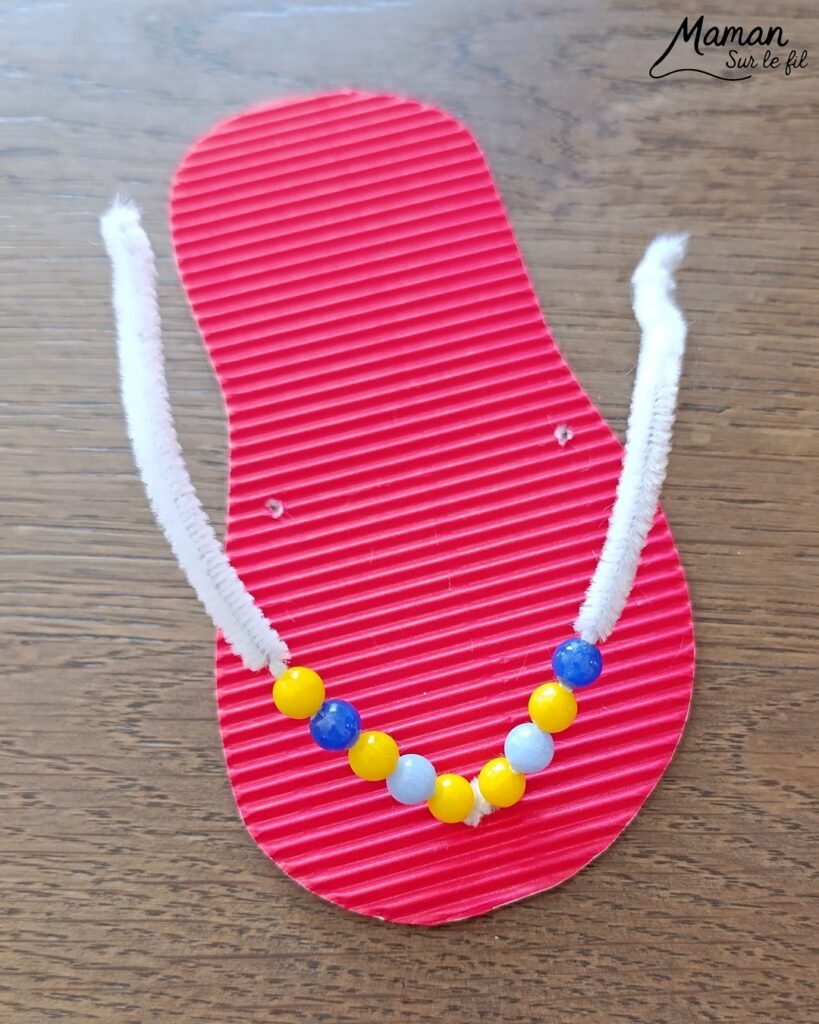 Fabriquer des tongs avec du carton ondulé, des fils chenille et des perles : activité créative et manuelle enfants - Base en carton ondulé - Lanière avec fils chenille insérés dans les trous - Décoration avec des perles enfilées sur les fils chenille - Motricité fine, précision, algorithme - Décoration DIY Fait maison - Arts visuels et Bricolage facile - Thème mer, océans, plage, été, vacances, vêtements, chaussures et accessoires - Bricolage et décoration sympa et facile - Arts visuels maternelle et élémentaire - Cycles 1 et 2 - Créativité - tutoriel photos et vidéo - mslf