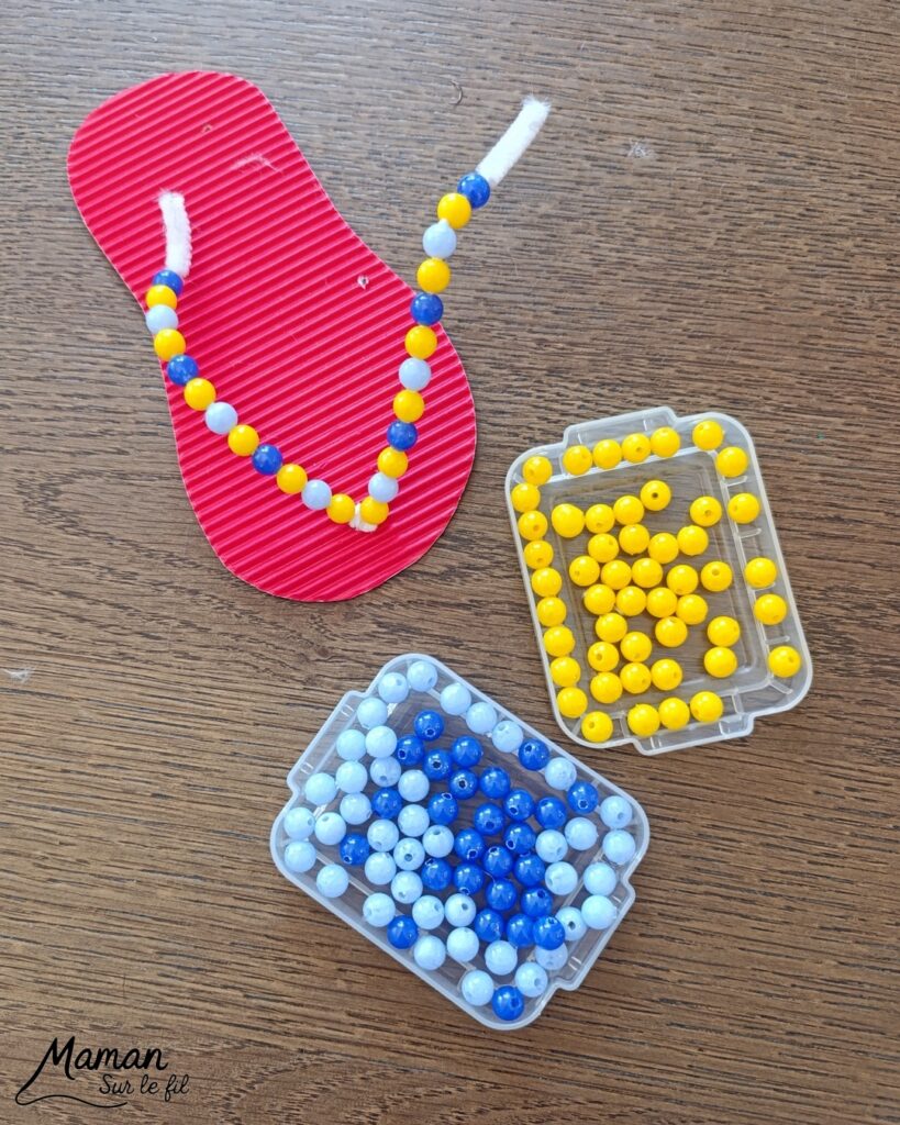 Fabriquer des tongs avec du carton ondulé, des fils chenille et des perles : activité créative et manuelle enfants - Base en carton ondulé - Lanière avec fils chenille insérés dans les trous - Décoration avec des perles enfilées sur les fils chenille - Motricité fine, précision, algorithme - Décoration DIY Fait maison - Arts visuels et Bricolage facile - Thème mer, océans, plage, été, vacances, vêtements, chaussures et accessoires - Bricolage et décoration sympa et facile - Arts visuels maternelle et élémentaire - Cycles 1 et 2 - Créativité - tutoriel photos et vidéo - mslf